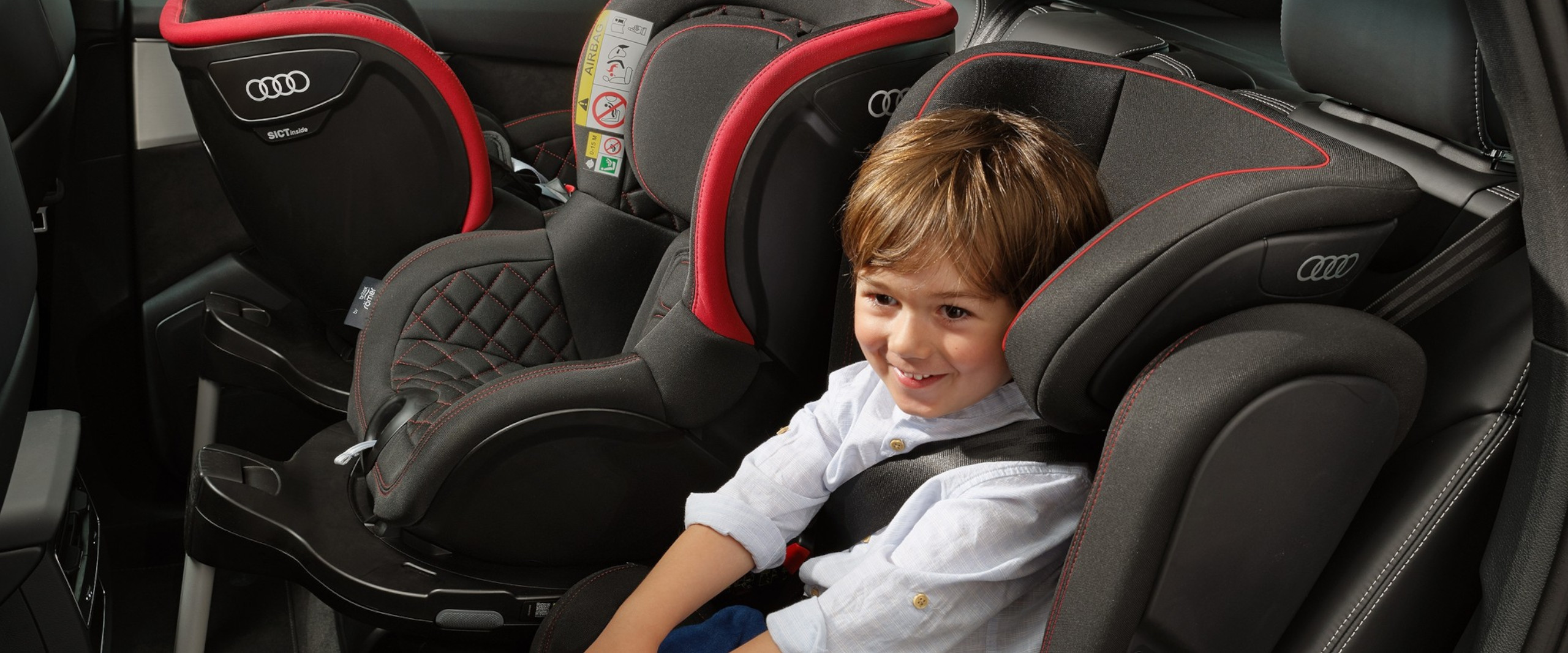 Original Kindersitz von Audi Kind sitzt in einem Kindersitz von Audi